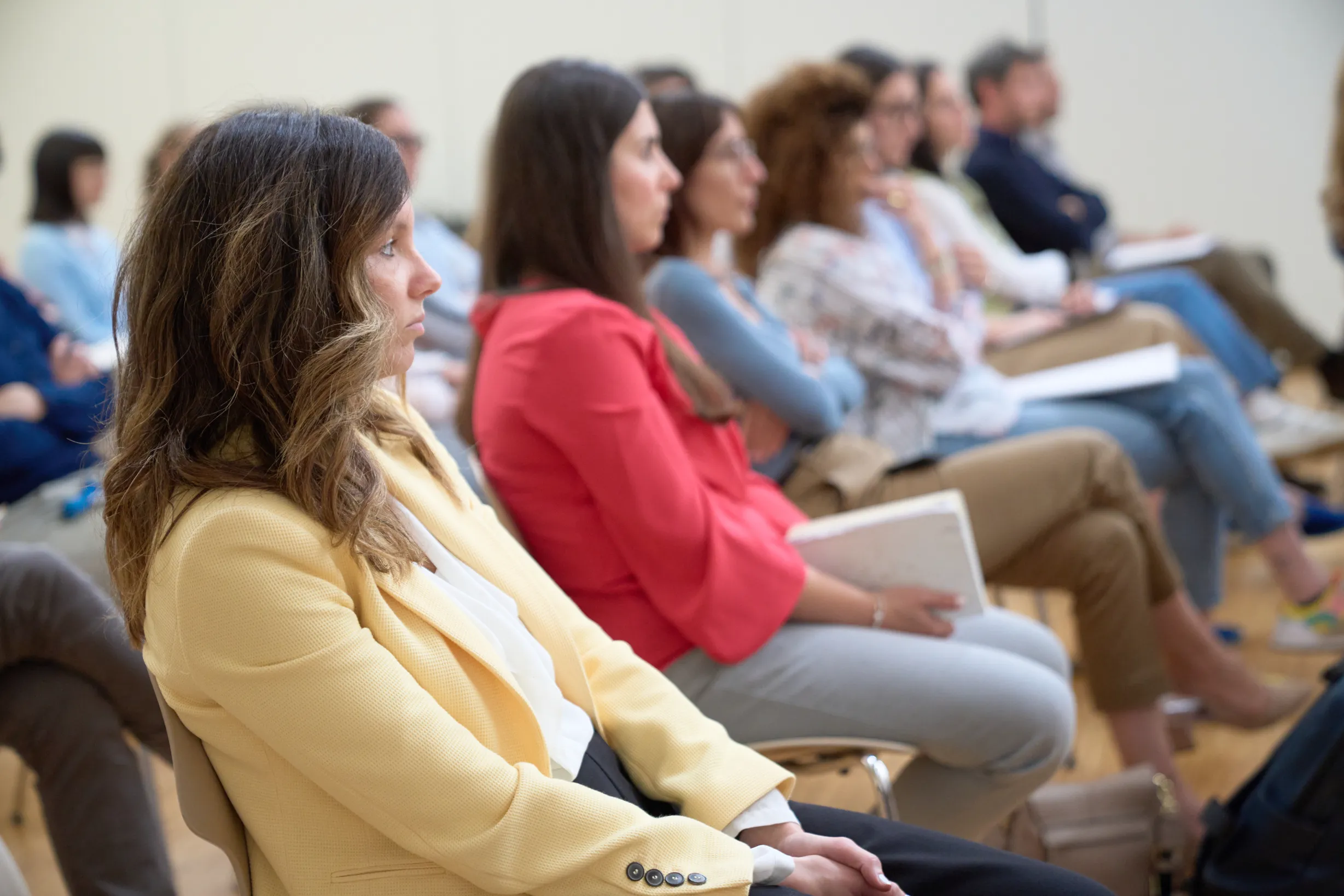 Donne e uomini in un seminario, ascoltando attentamente il relatore con quaderni e appunti