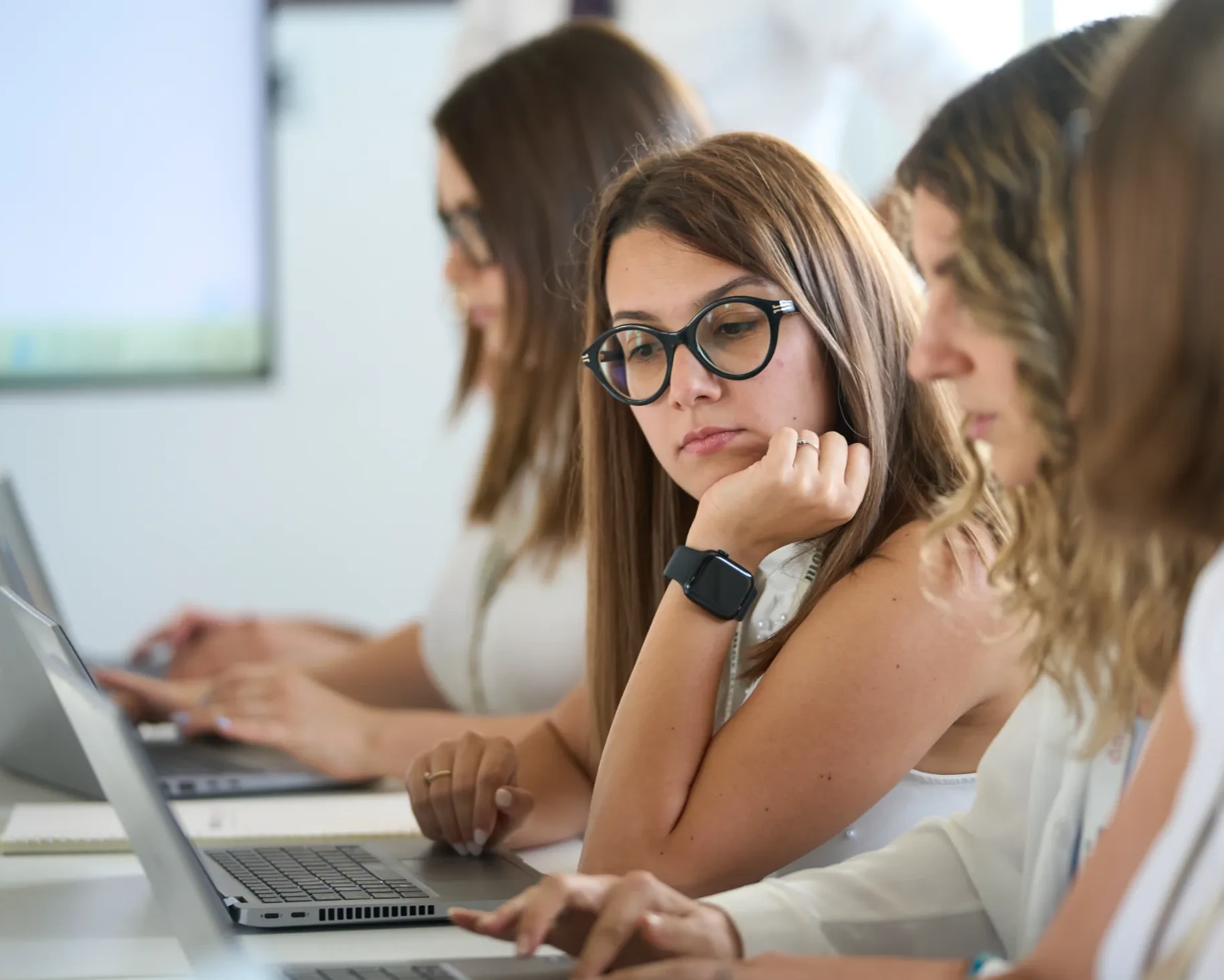 Gruppo di donne al lavoro su laptop in un ambiente moderno e luminoso