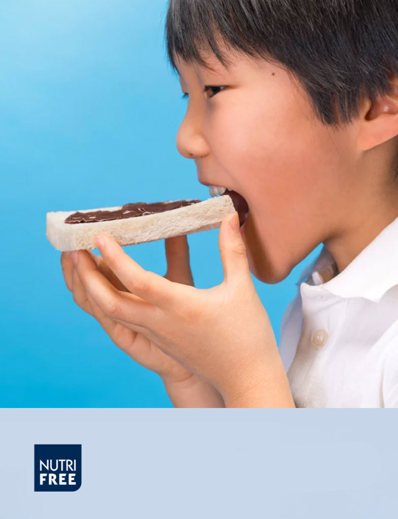 Ragazzo che assapora una fetta di pane dolce senza glutine con crema spalmabile al cioccolato