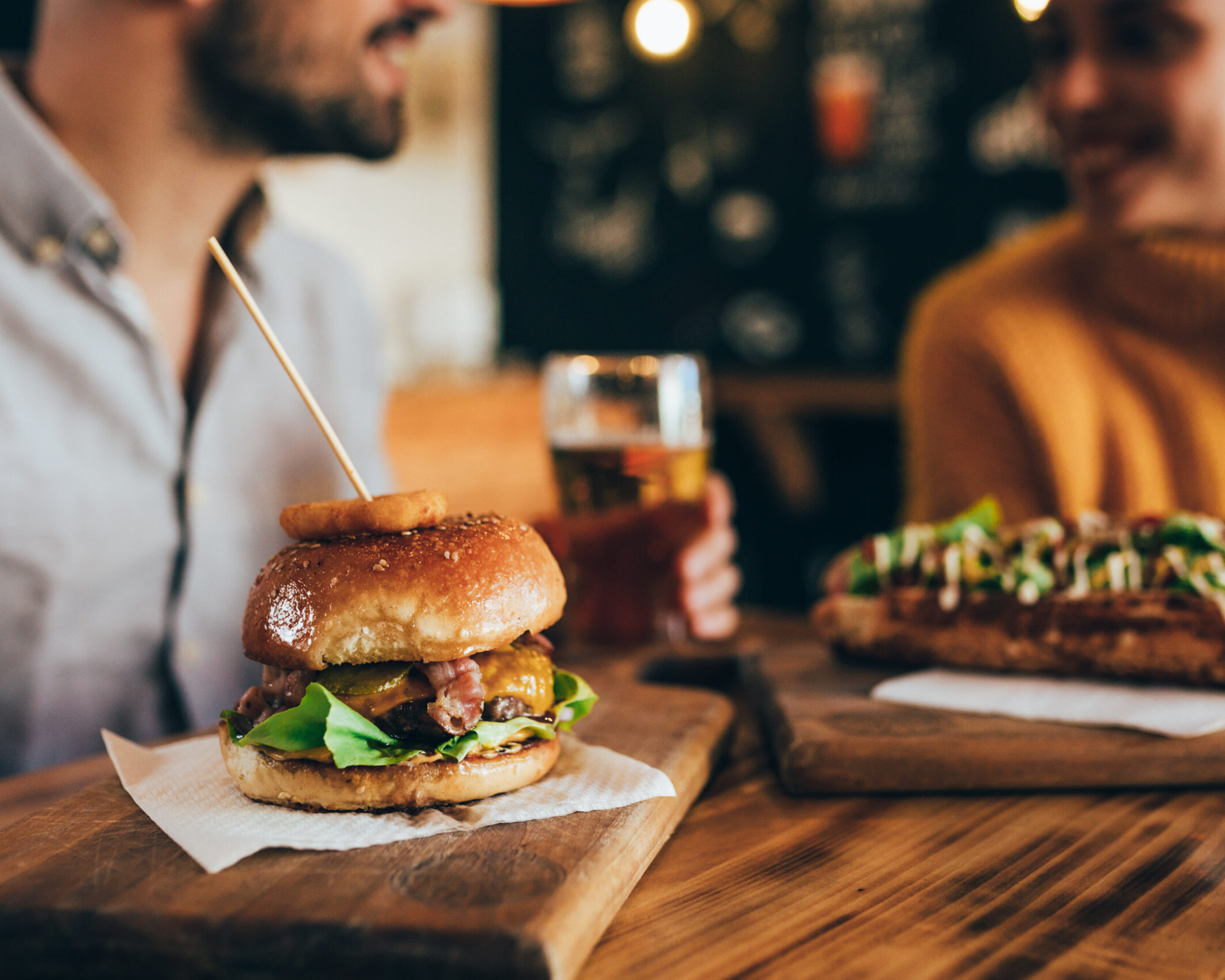 Due amici a tavola nel ristorante, hamburger delizioso e birra artigianale