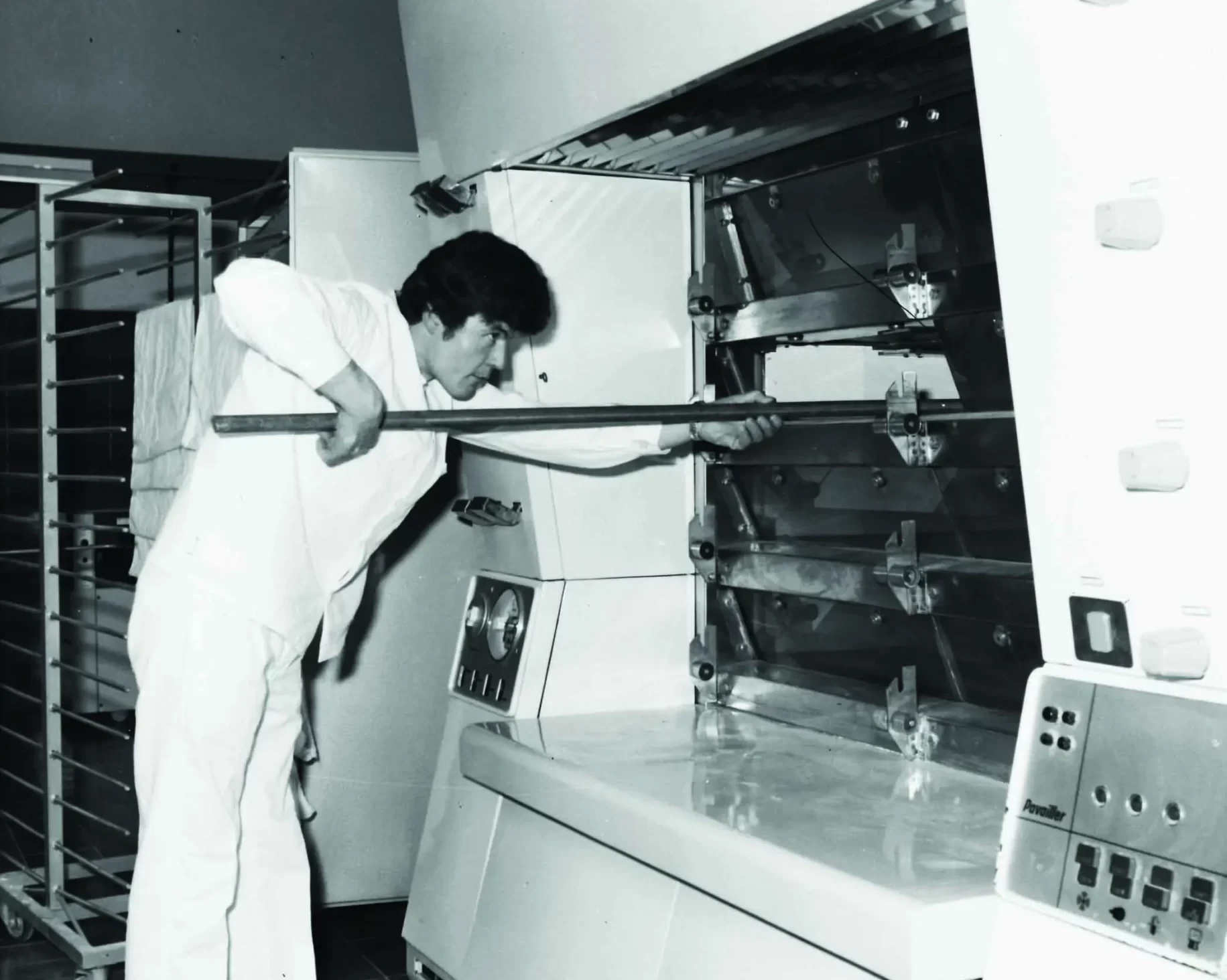 Un uomo che utilizza una macchina per panificazione in un laboratorio di produzione di pane