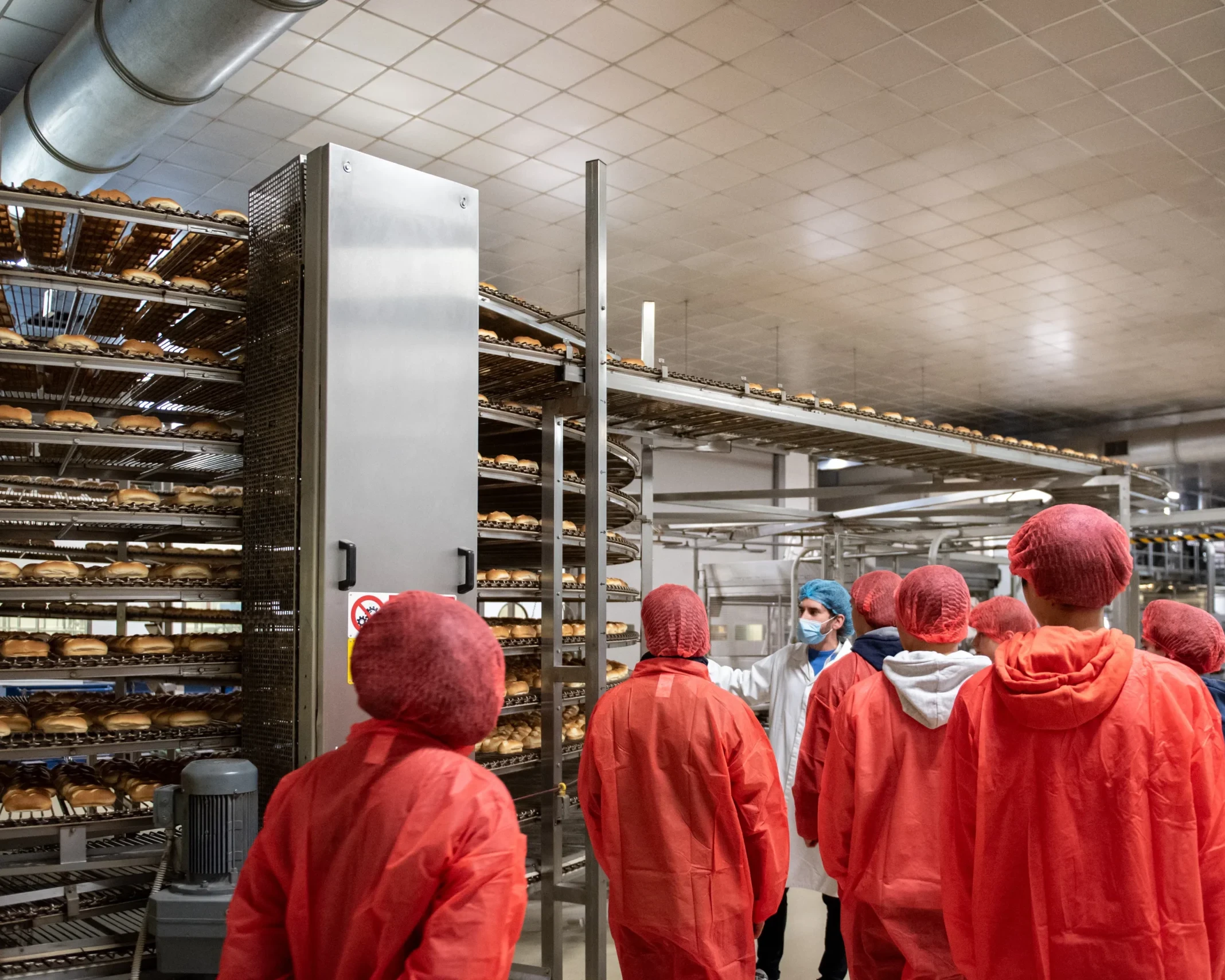 Gruppo di persone in abbigliamento protettivo visitano un impianto di produzione alimentare